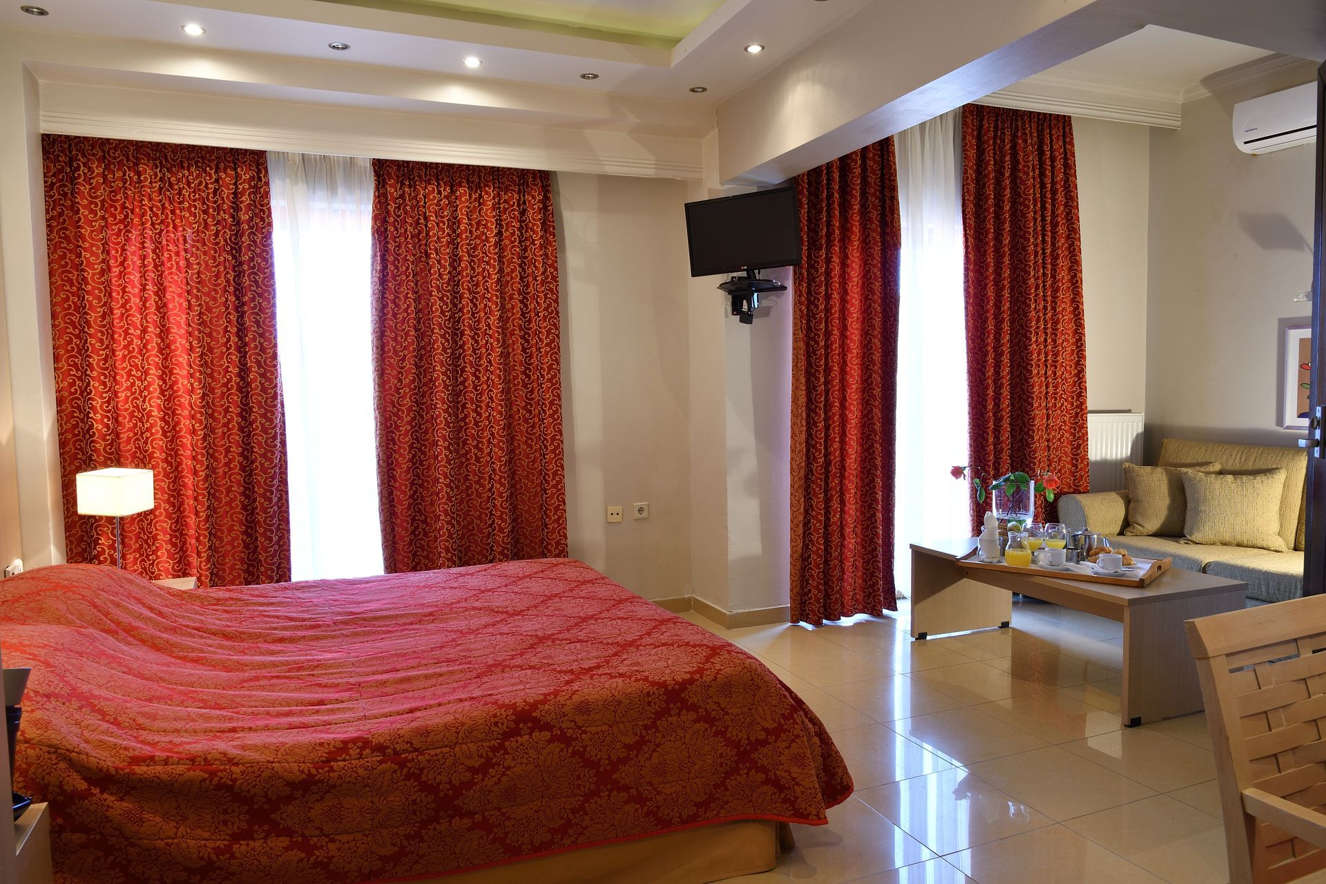 A hotel room with a bed , couch , coffee table and television.