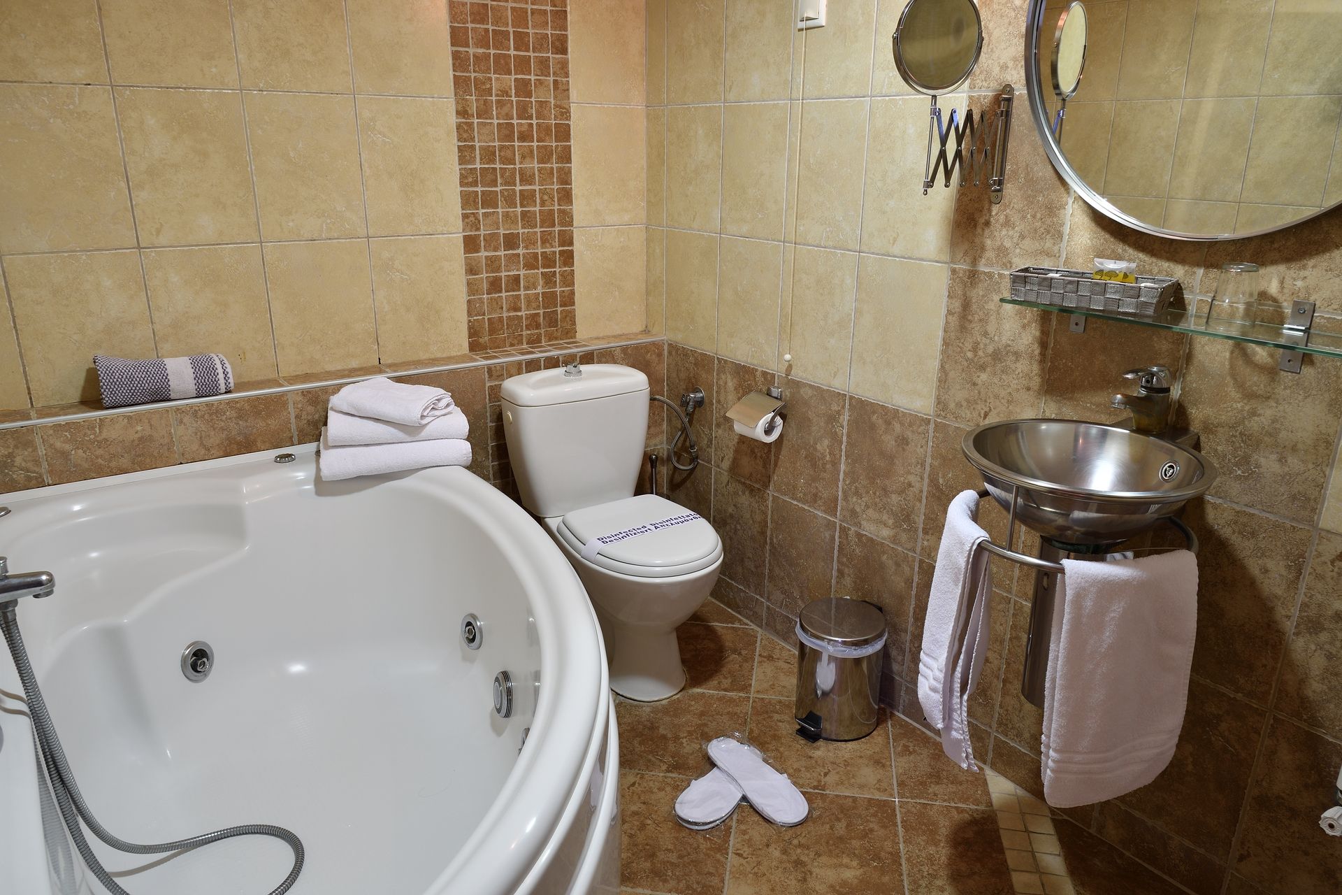 A bathroom with a jacuzzi tub , toilet , sink and mirror.