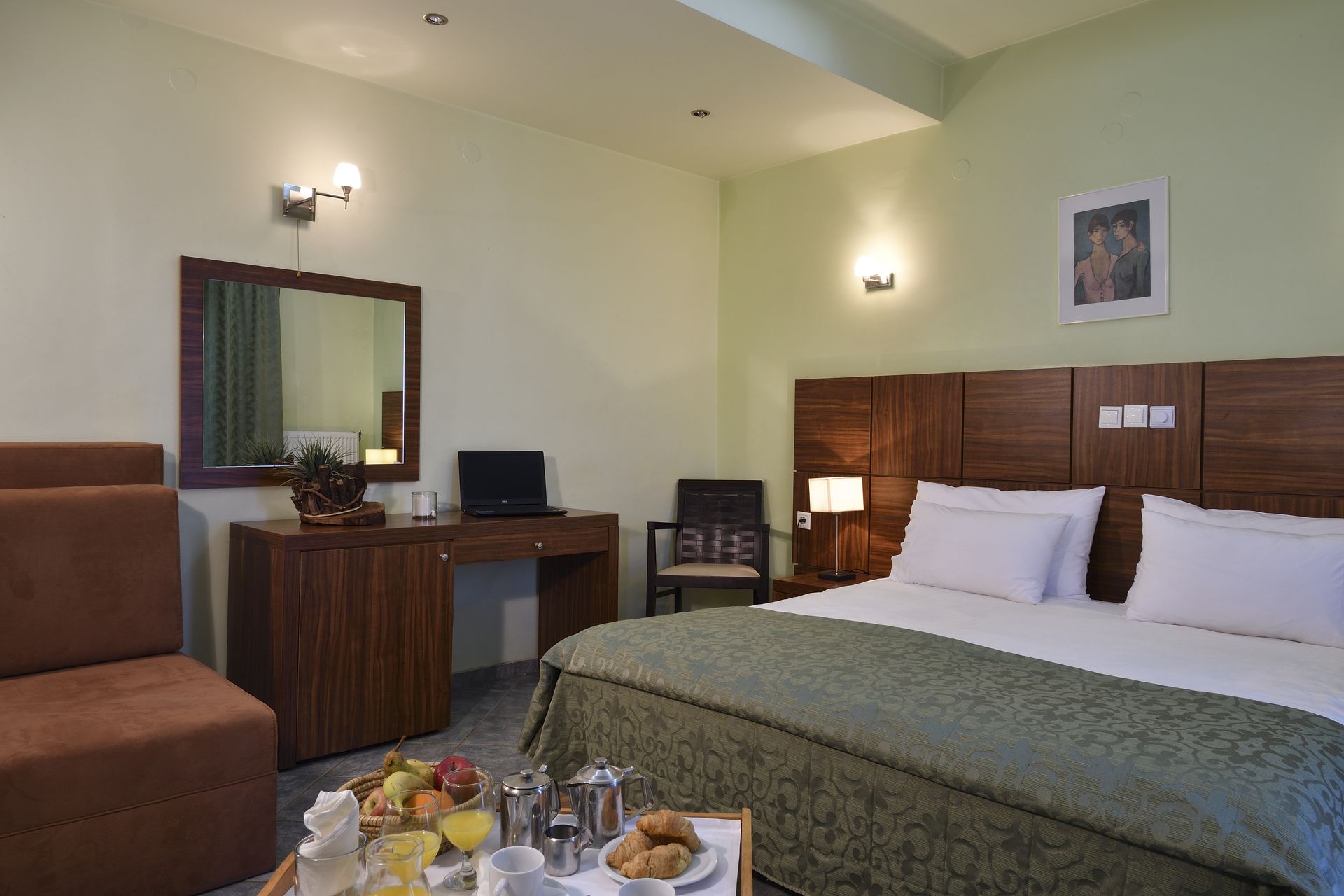 A hotel room with a bed , chair , desk and mirror.