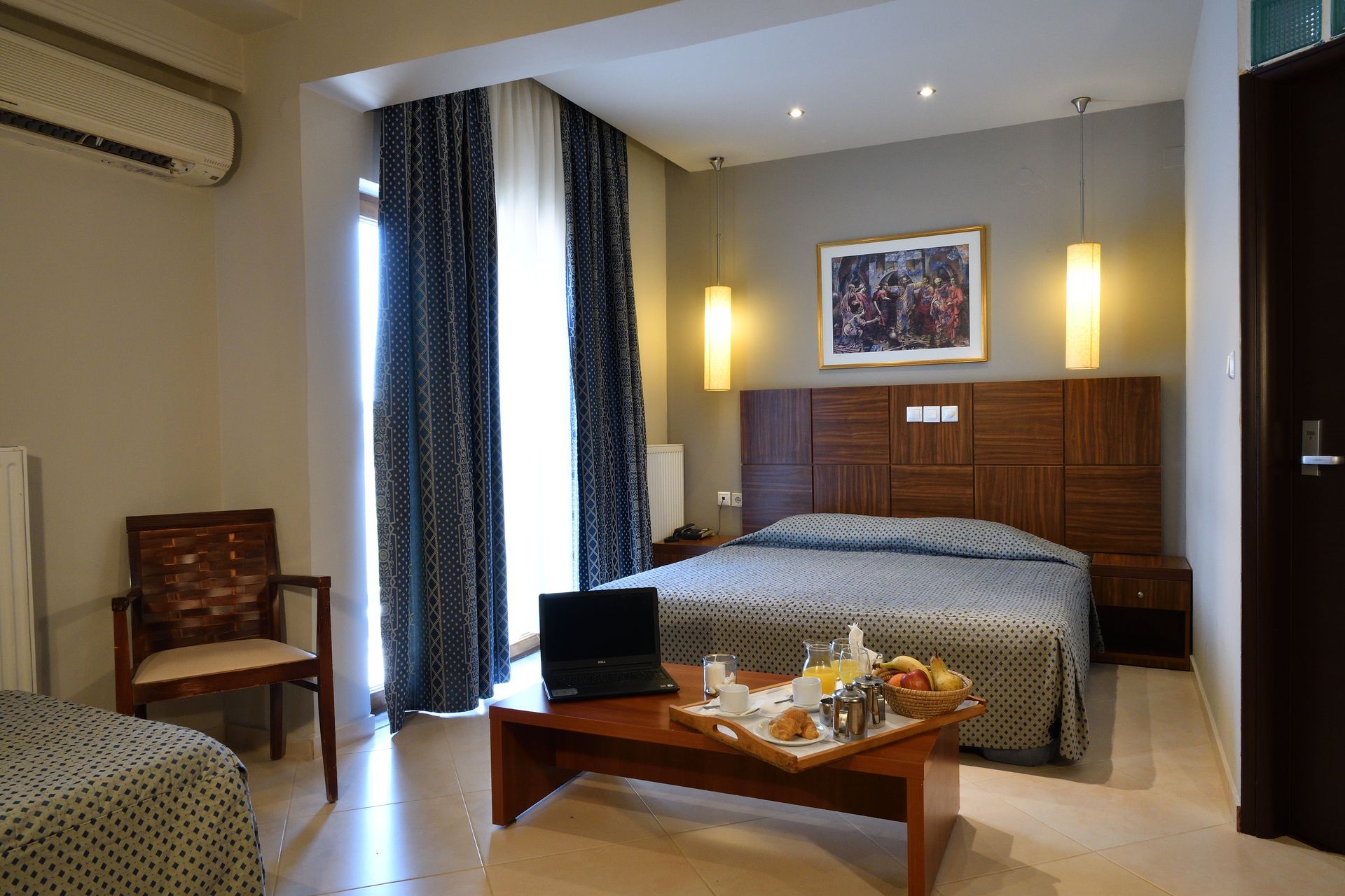 A hotel room with a large bed and a coffee table with a laptop on it.