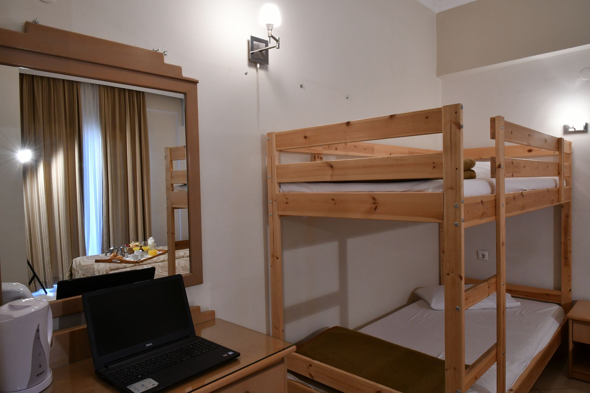 A room with bunk beds and a laptop on a desk.