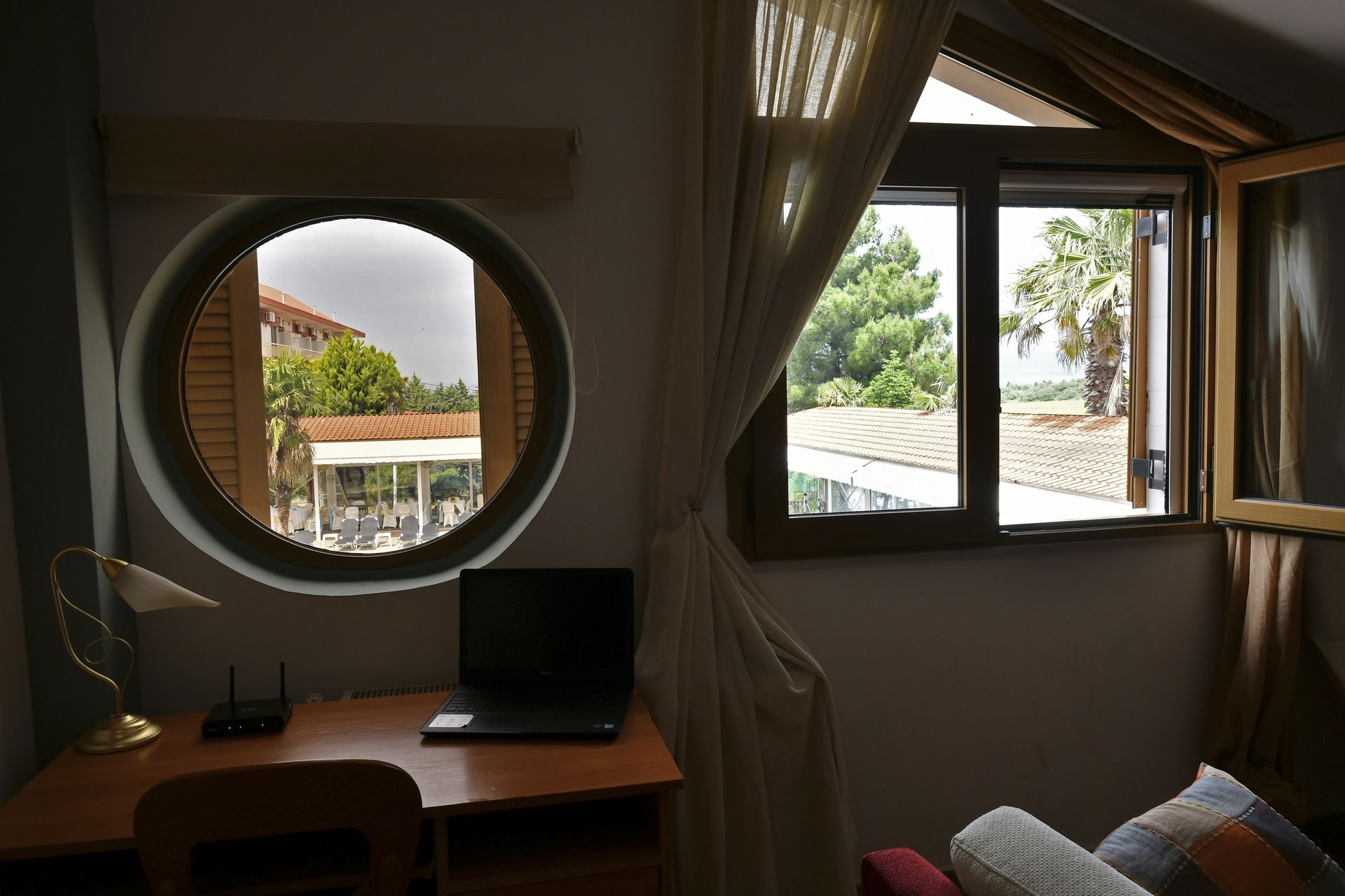 A room with a round window and a desk with a laptop on it
