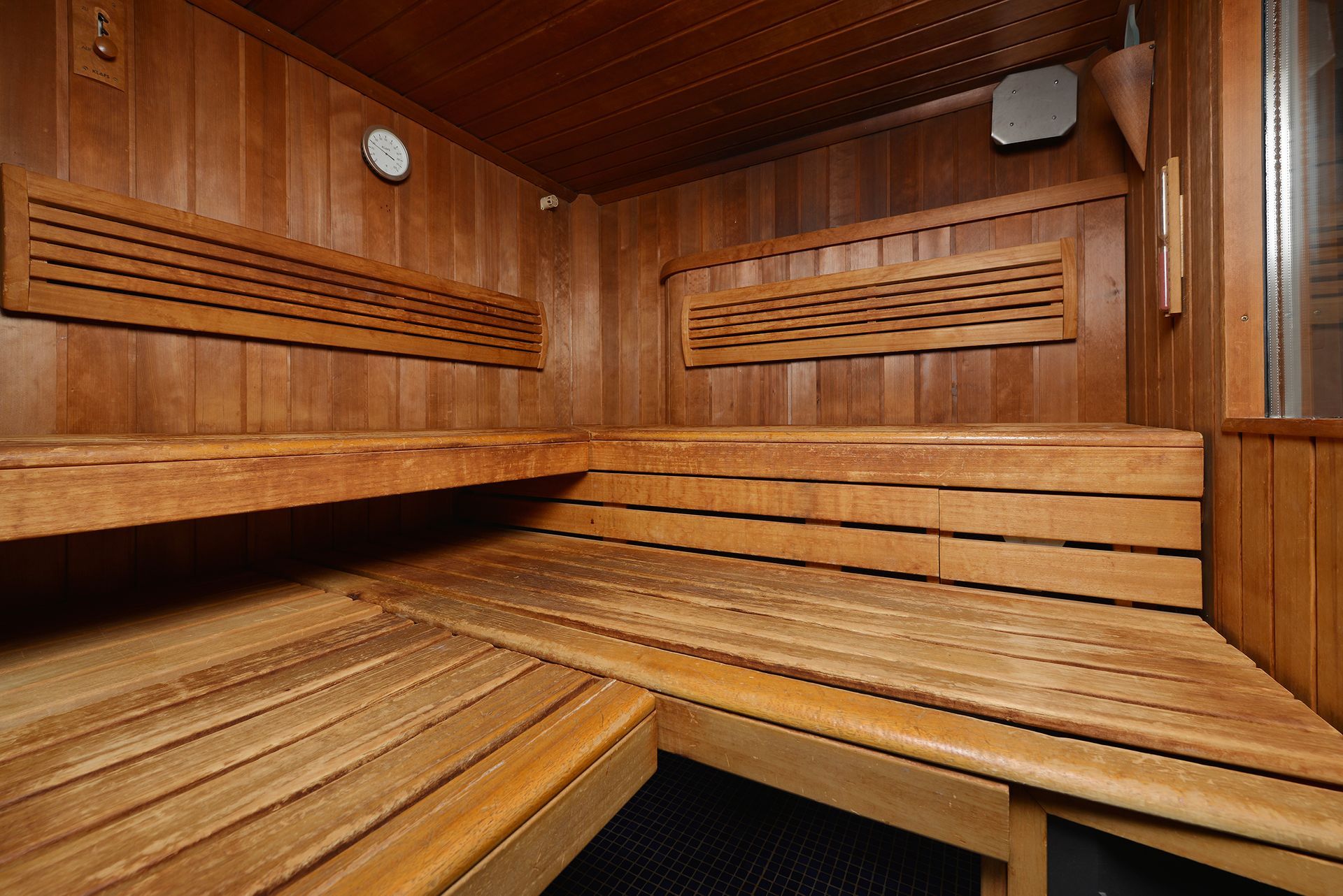 The inside of a wooden sauna with wooden benches and a ceiling.