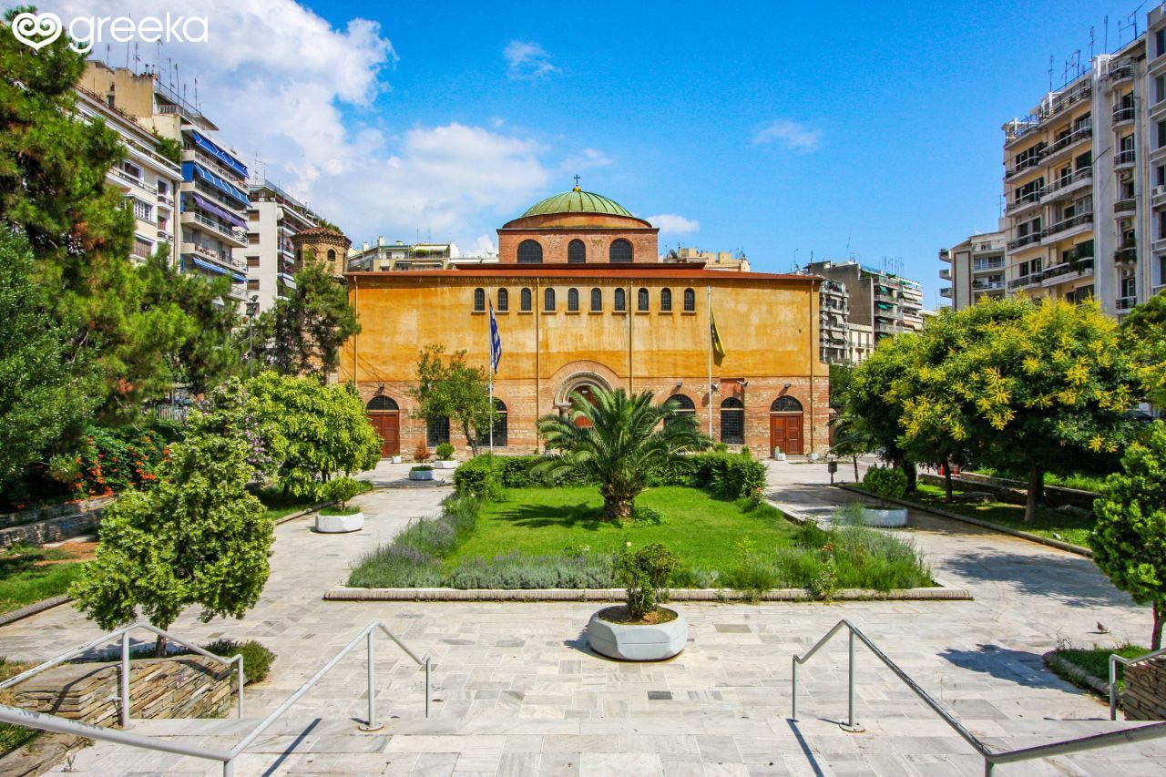 There is a large building in the middle of a park surrounded by trees.