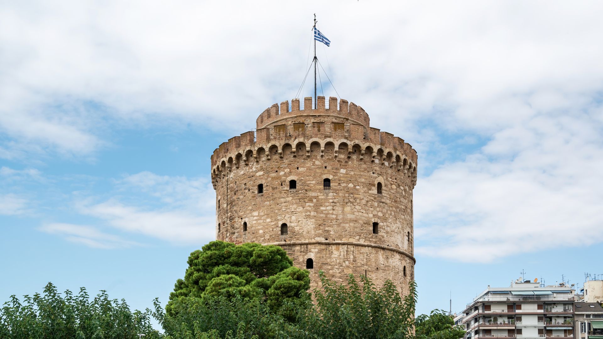 A large stone tower with a flag on top of it.