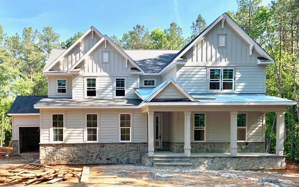 Two-story house with gray siding, stone base, and a front porch.