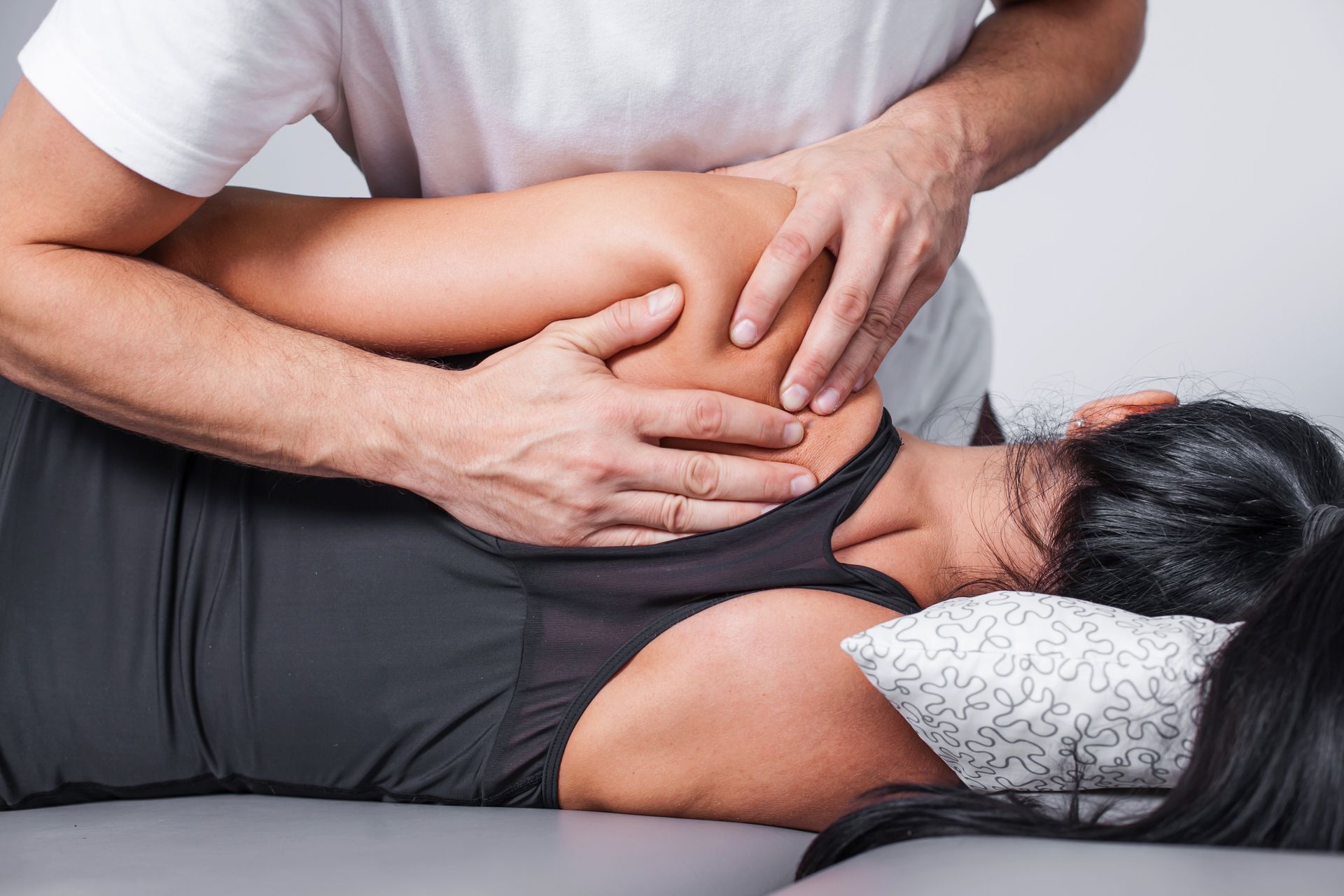A person receives a shoulder massage while lying down.