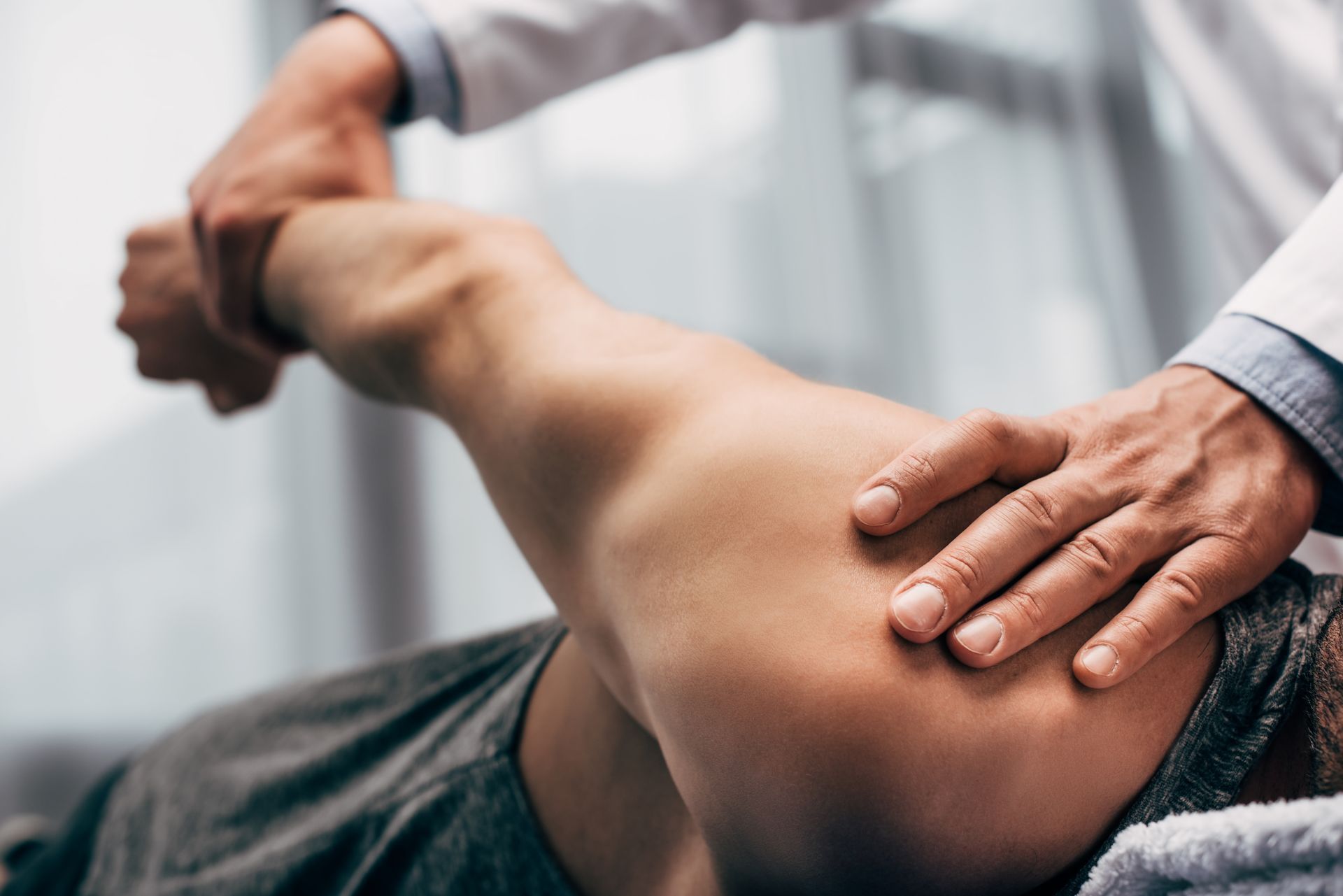 Doctor manipulating a patient's arm during a physical examination, indoors.
