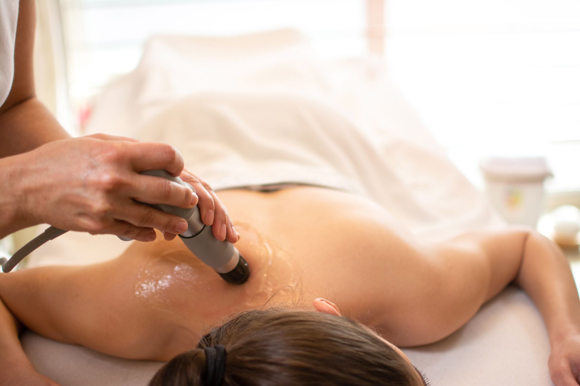 A person receiving shockwave therapy on their back, in a medical setting.