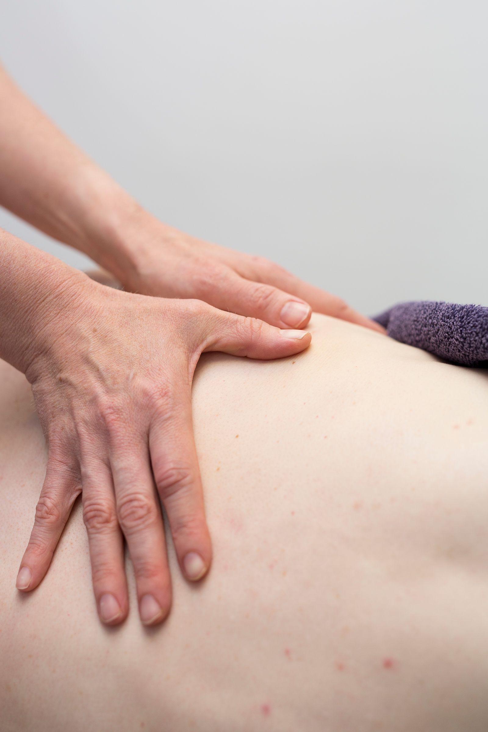 Hands giving a back massage on a light-skinned person.