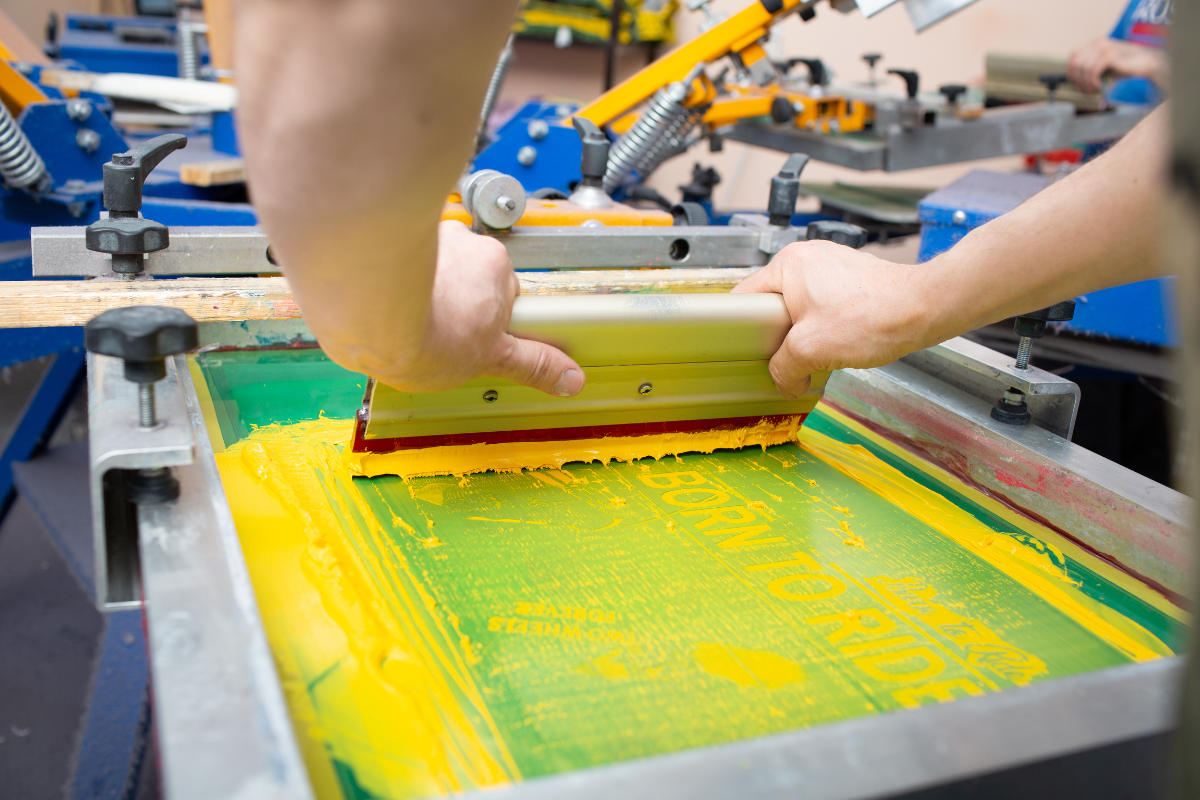 A person is using a screen printing machine to print a picture.