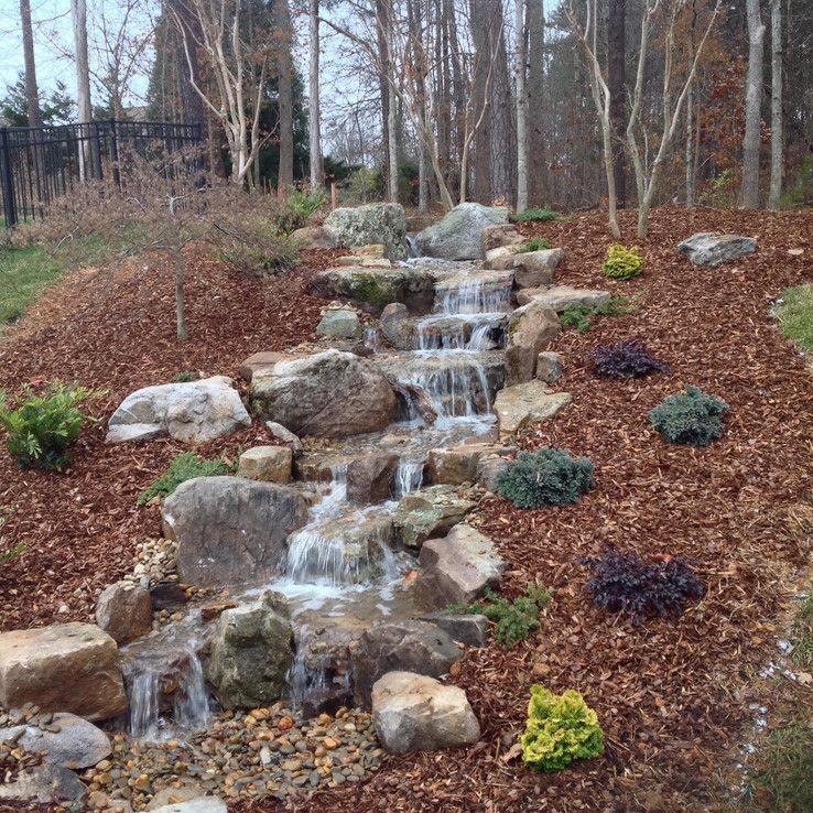 Rock garden waterfall cascading over stones in a wooded landscape with autumn leaves