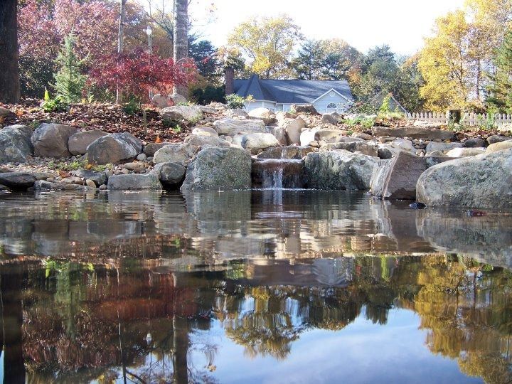 Rock garden waterfall with autumn trees reflected in a calm pond