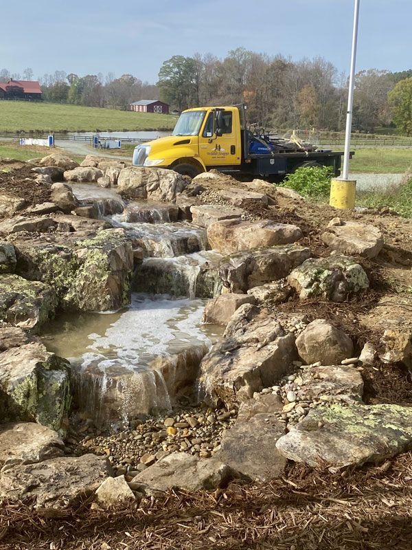 Yellow truck beside a small rocky waterfall in a landscaped park