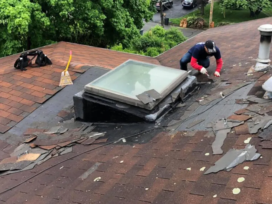 A man is working on a roof with a skylight.