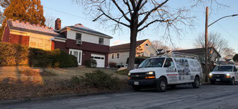 A couple of vans parked in front of a house.