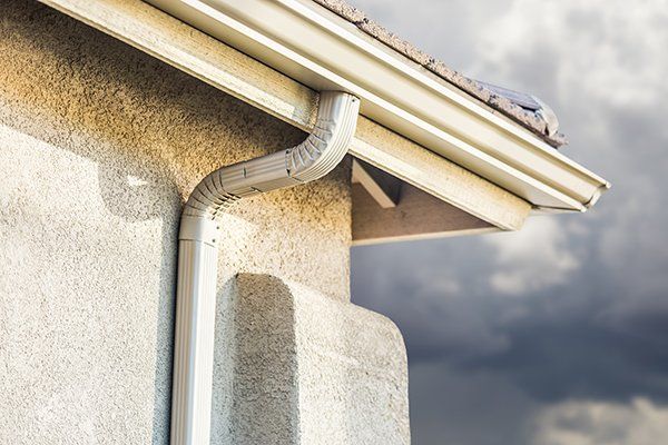 A close up of a gutter on the side of a house.