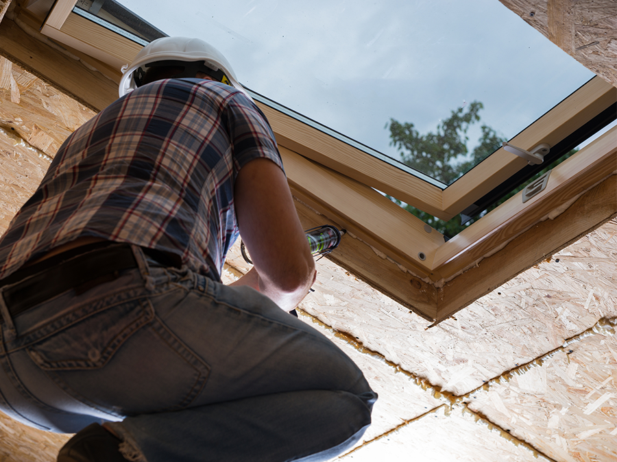 A man is working on a skylight in a house.
