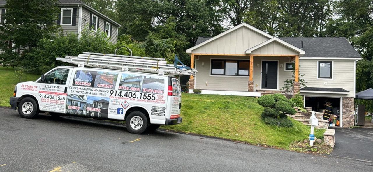 White work van with ladders parked on a hill next to a two-story house with renovations.