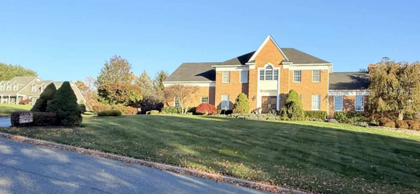 A large brick house with a green lawn under a blue sky.