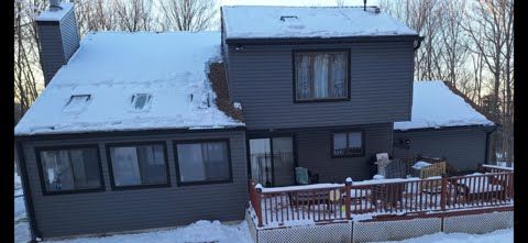A large house with a lot of windows is covered in snow.
