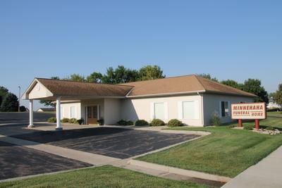 A white building with a brown roof and a sign that says minnehaha funeral home.