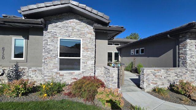 Modern home with stone and stucco exterior, pathway, and lush landscaping.
