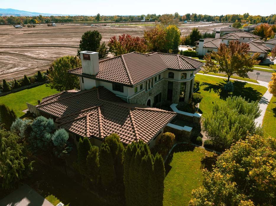 Luxury home with a terracotta tile roof, surrounded by green lawns and trees.