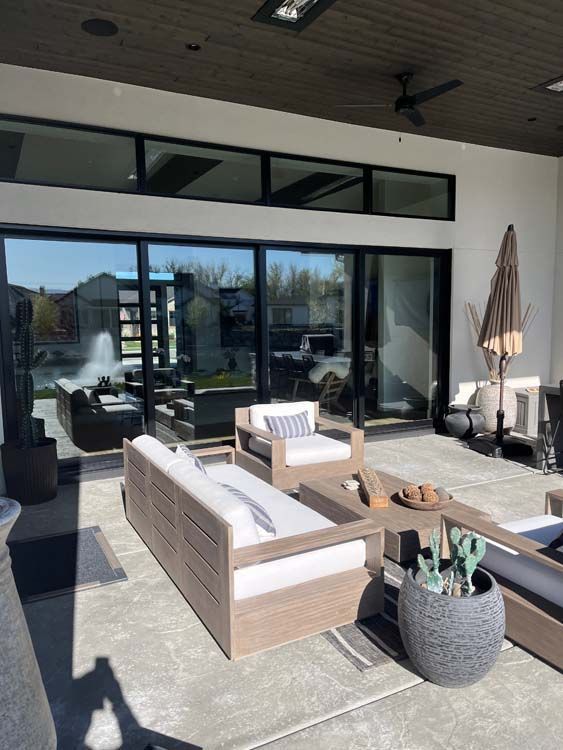 Patio with modern furniture, large sliding glass doors, and a fountain in the distance.