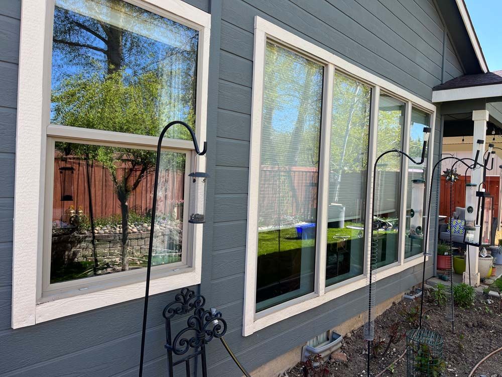 Exterior view of gray house with several windows, white trim, and a small garden.