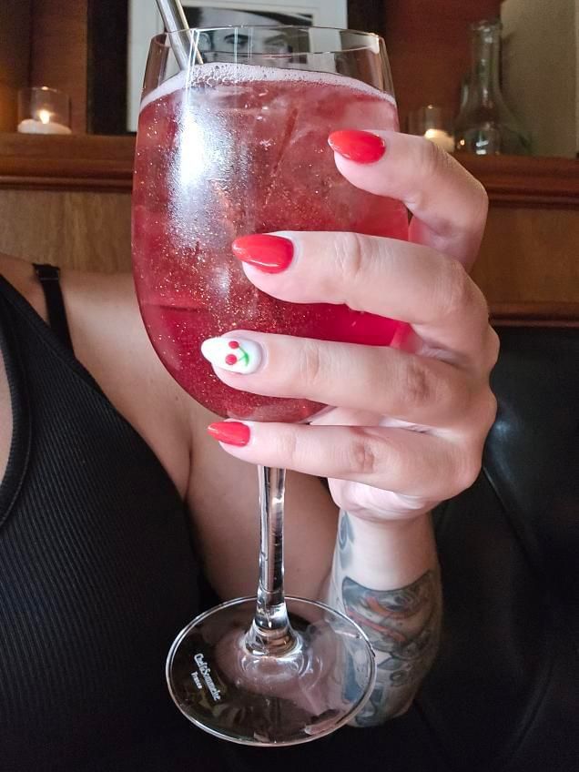 A woman with red nails is holding a glass of wine