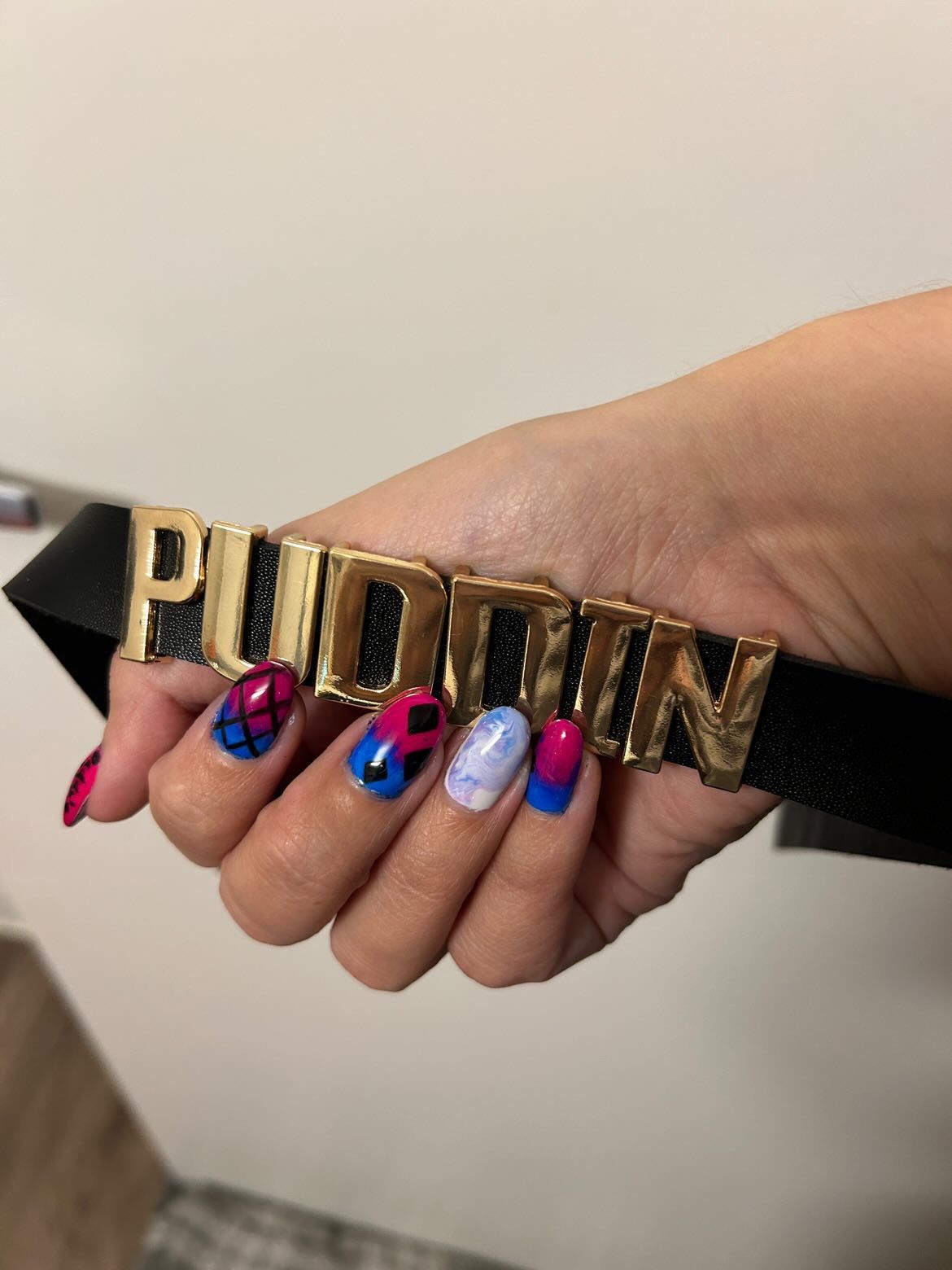 A woman is holding a choker with the word puddin on it