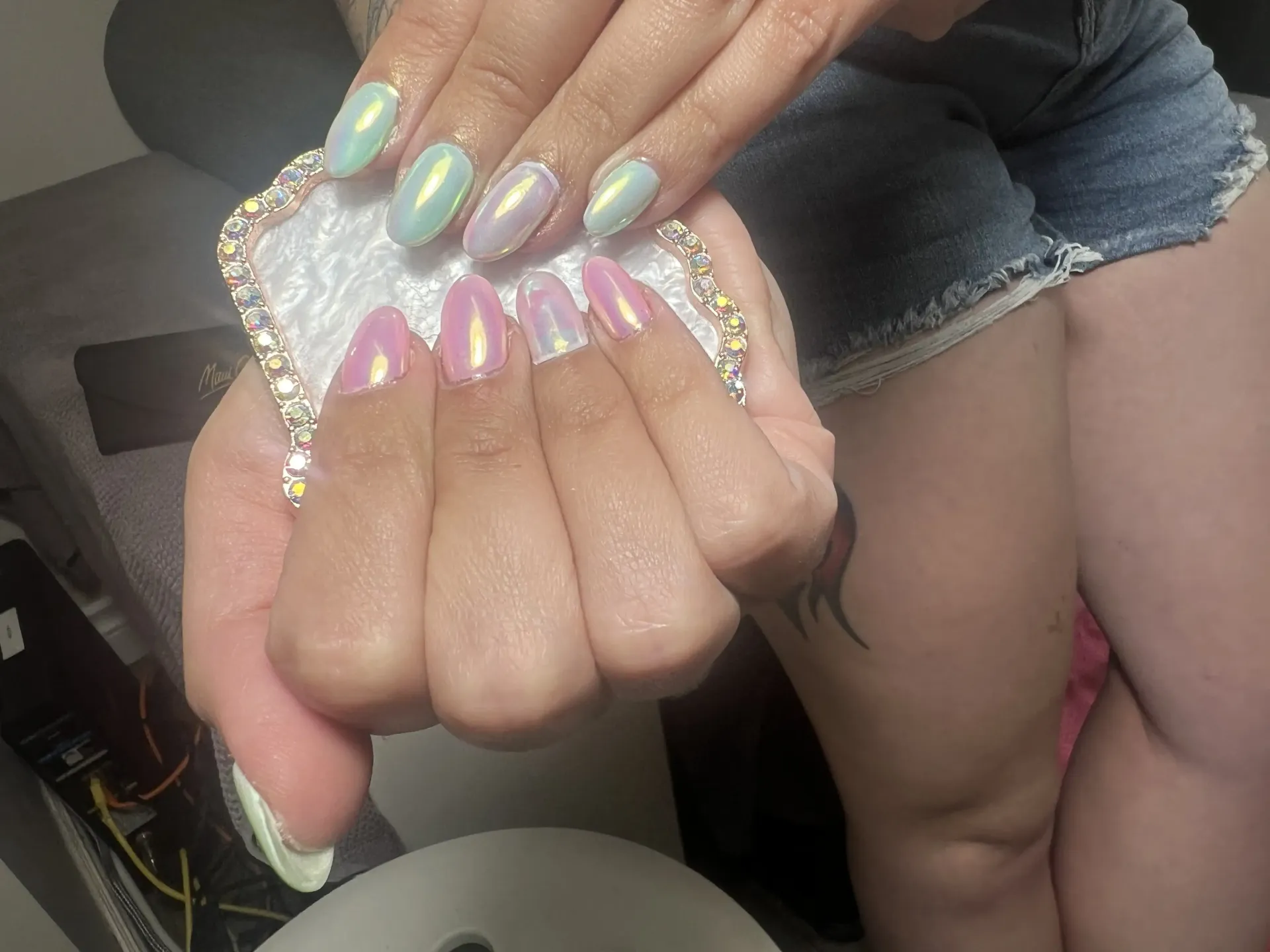 A woman is holding a piece of paper with her nails painted in different colors.
