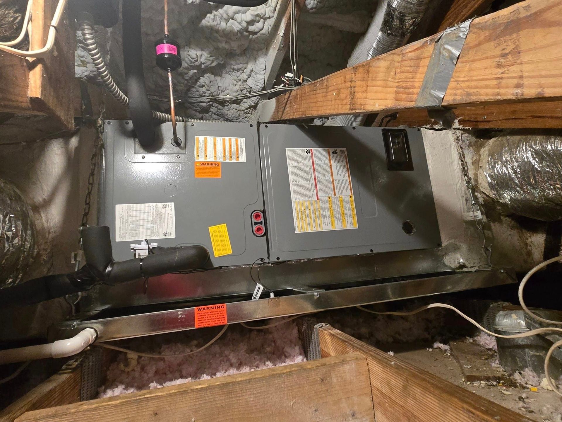 An air conditioner is sitting in the attic of a house.