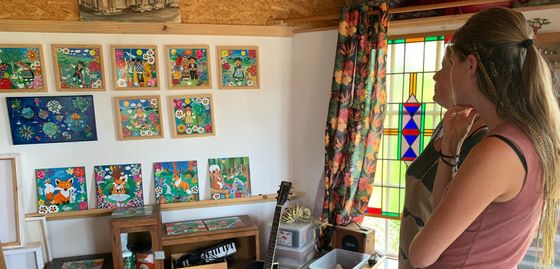 Iemand bekijkt kleurrijke muurdecoratie in een gezellige kamer met een glas-in-loodraam.