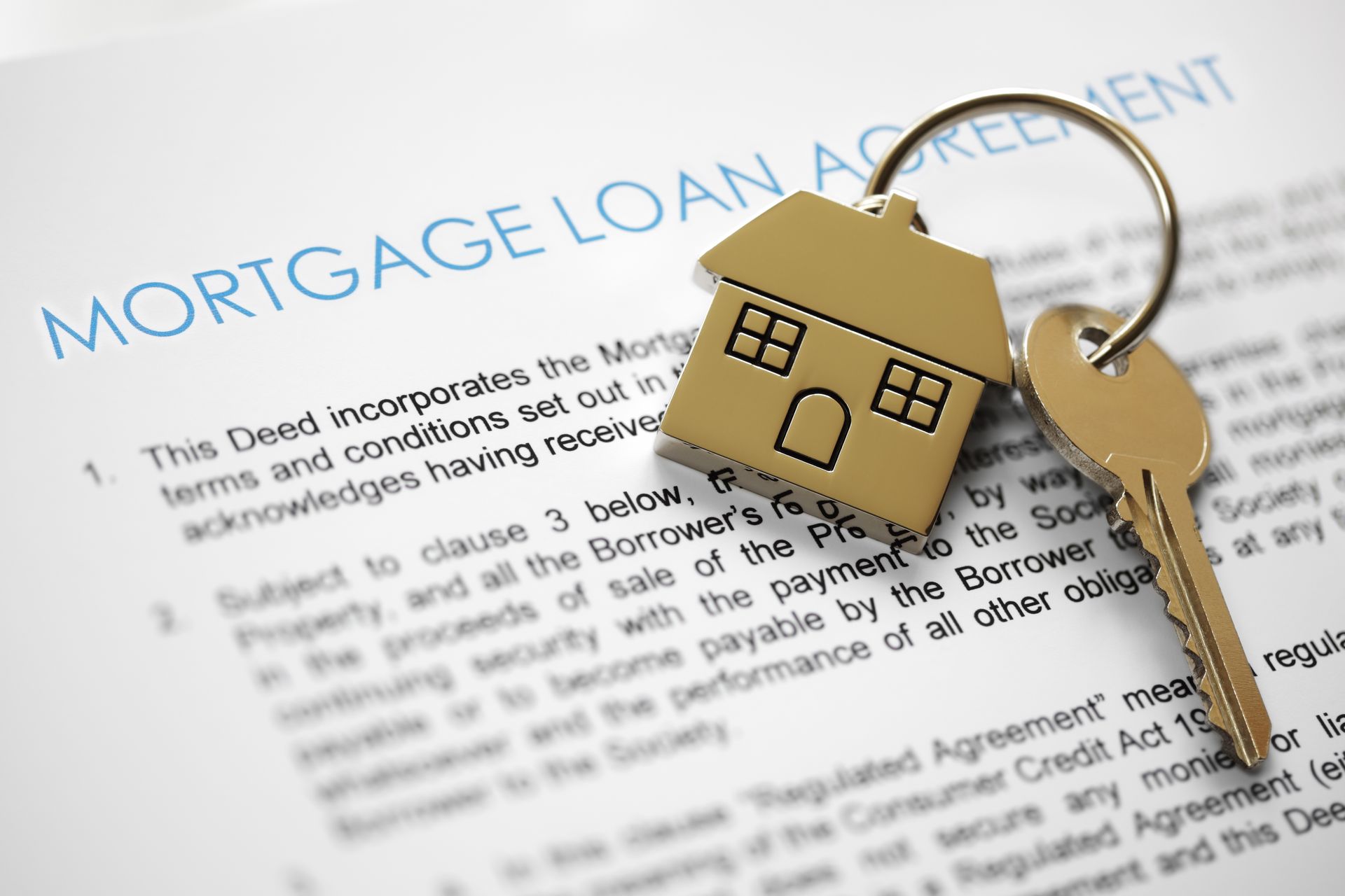 Mortgage loan agreement with house-shaped keychain and key resting on the document.