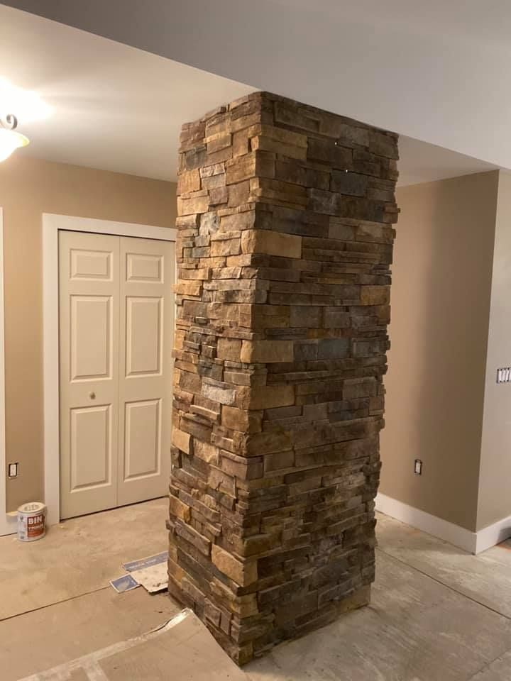 Stone-covered pillar in a room with a white door, beige walls, and light-colored flooring.