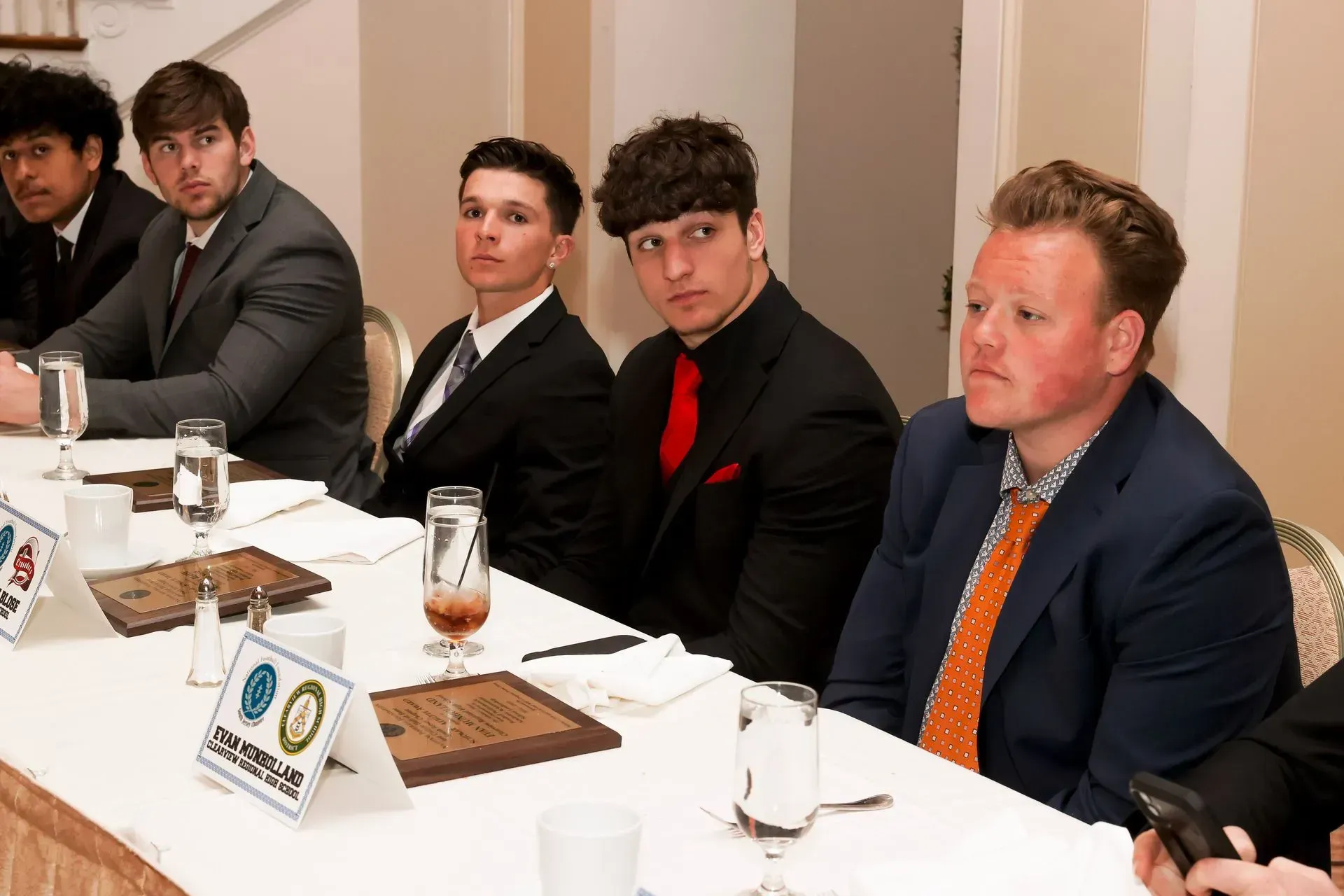 a group of men are sitting at a table with a sign that says ' sponsors ' on it
