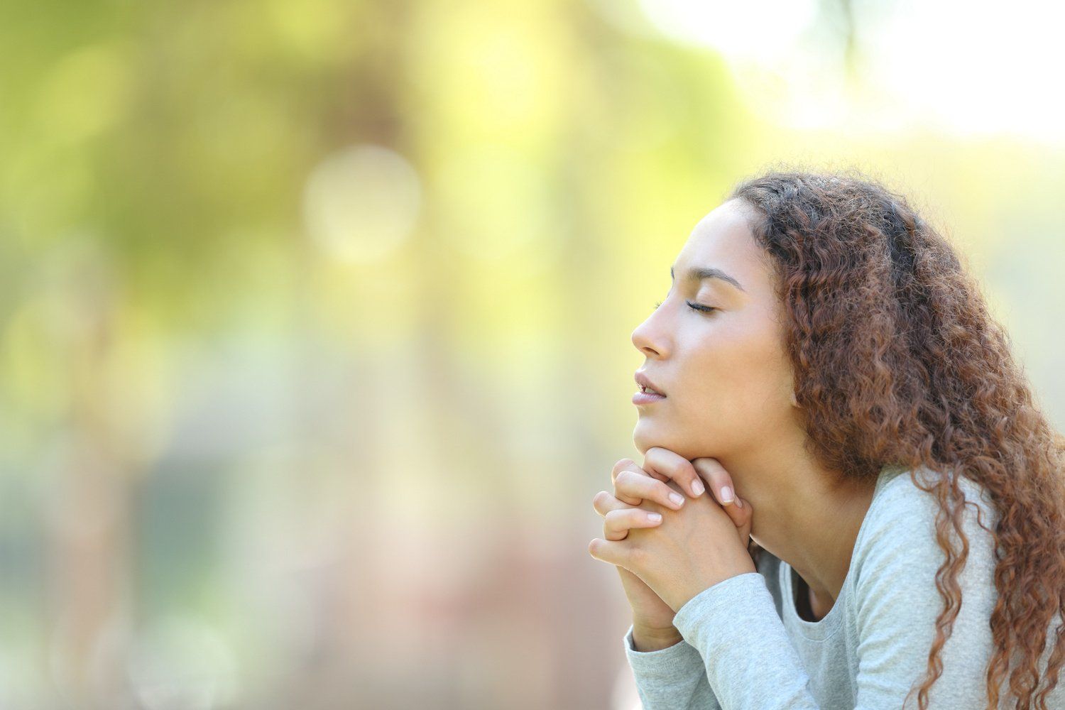 woman with folded hands eyes closed thinking