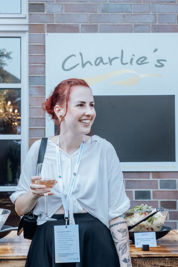 Lächelnder Mann mit grau meliertem Bart und Brille vor dunklem Hintergrund.