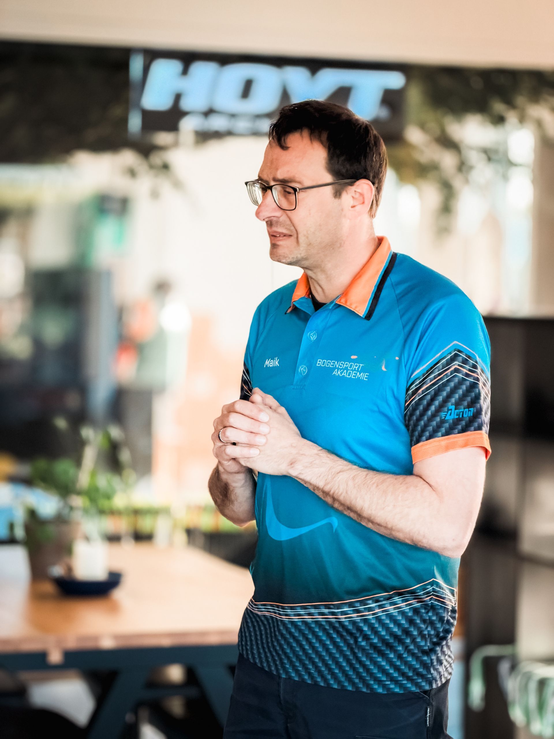 Zwei Männer essen an einem Imbissstand. Einer mit Bart lächelt. Der Tisch ist rot-weiß gemustert. Schild: „Vorspeisen“.