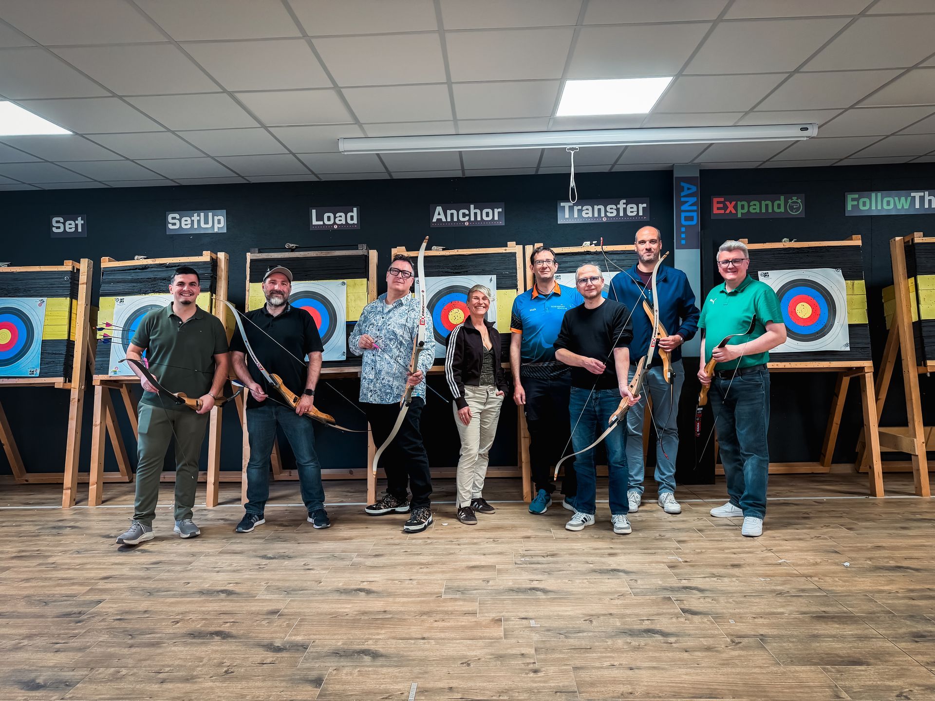 In einer Indoor-Golfanlage schauen sich Leute auf Bildschirmen Golf an. Einige tragen Weihnachtsmannmützen.