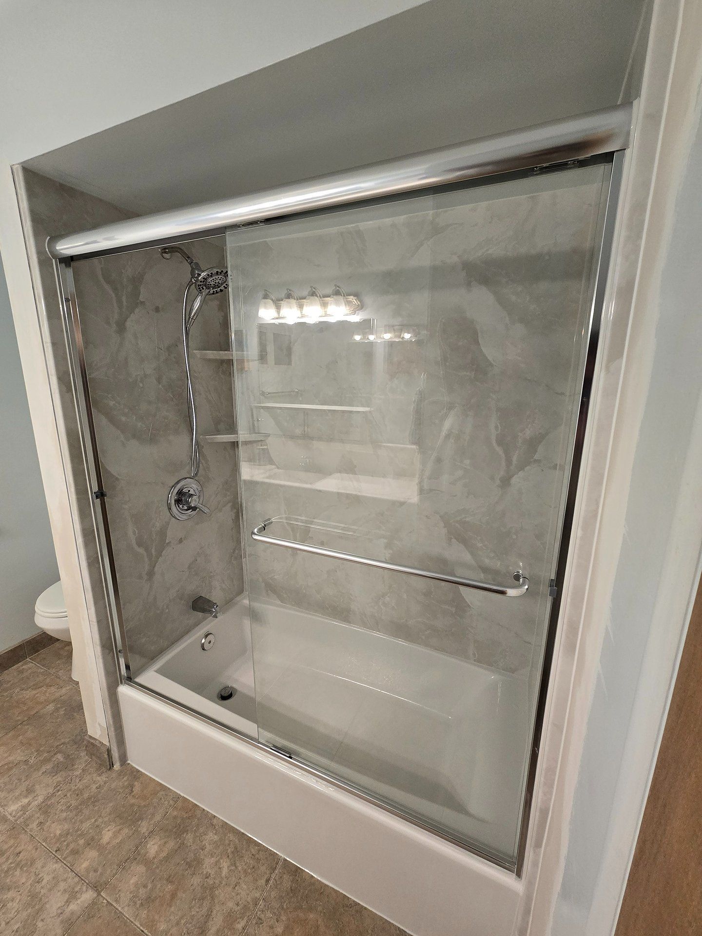 Wall-mounted recessed shower niche with a clear glass door and exposed plumbing inside
