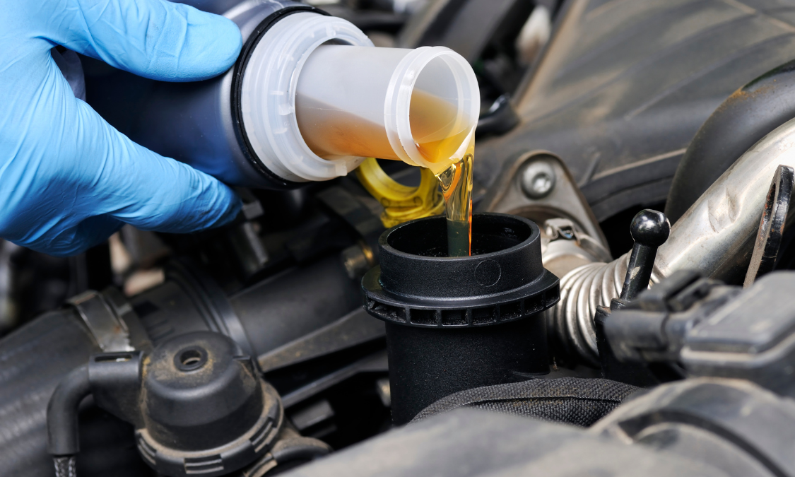 Person pouring oil from a Shell MAXI bottle into a car engine.