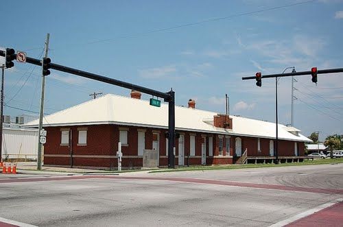 Brick building with a white roof, located at a street intersection. Traffic lights are visible.