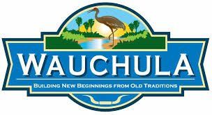 Logo for Wauchula, Florida, featuring a crane in front of a lake and trees under a sun. Text reads