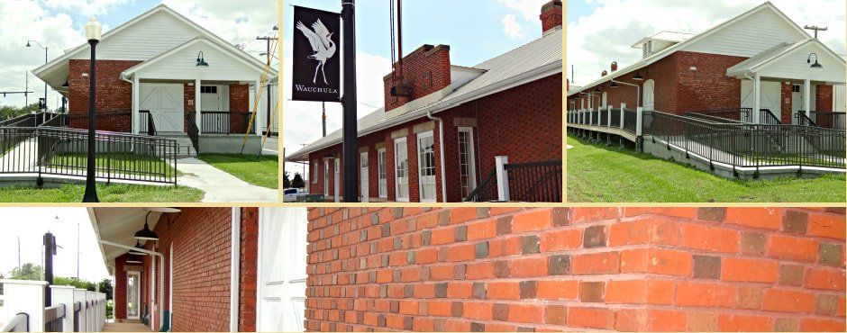A red brick building with white trim and a banner. Includes a ramp, grass, and a light post.