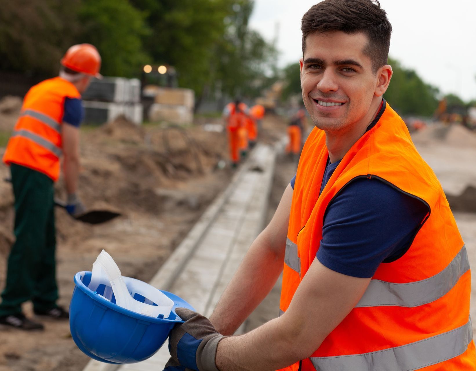 A construction worker in an orange vest smiles because he uses soy methyl ester to clean asphalt