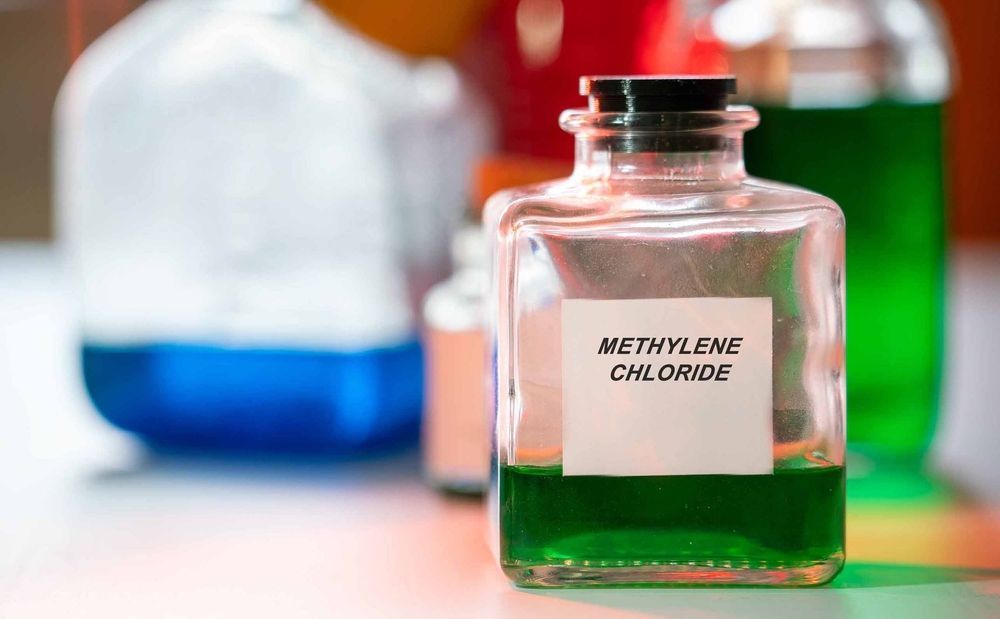 A lab bottle containing green liquid labeled