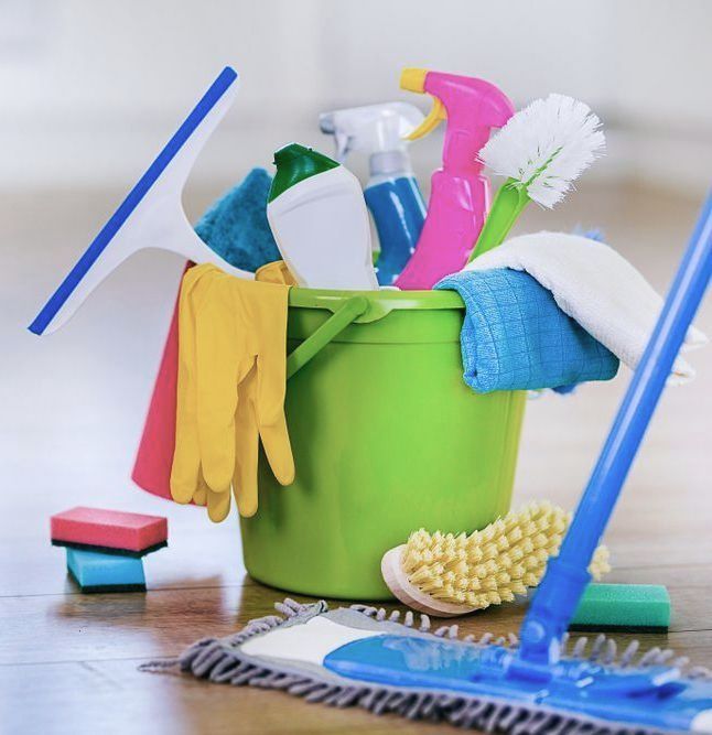a green bucket holds various cleaning products and agents, some of which may contain dangerous VOCs